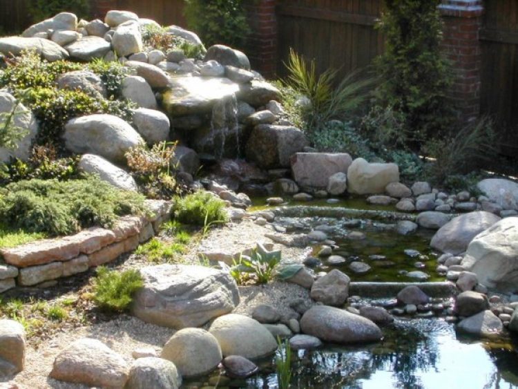 Un exemple de jardin de rocaille combiné avec un étang et une cascade. Faites attention à la forme arrondie des pierres