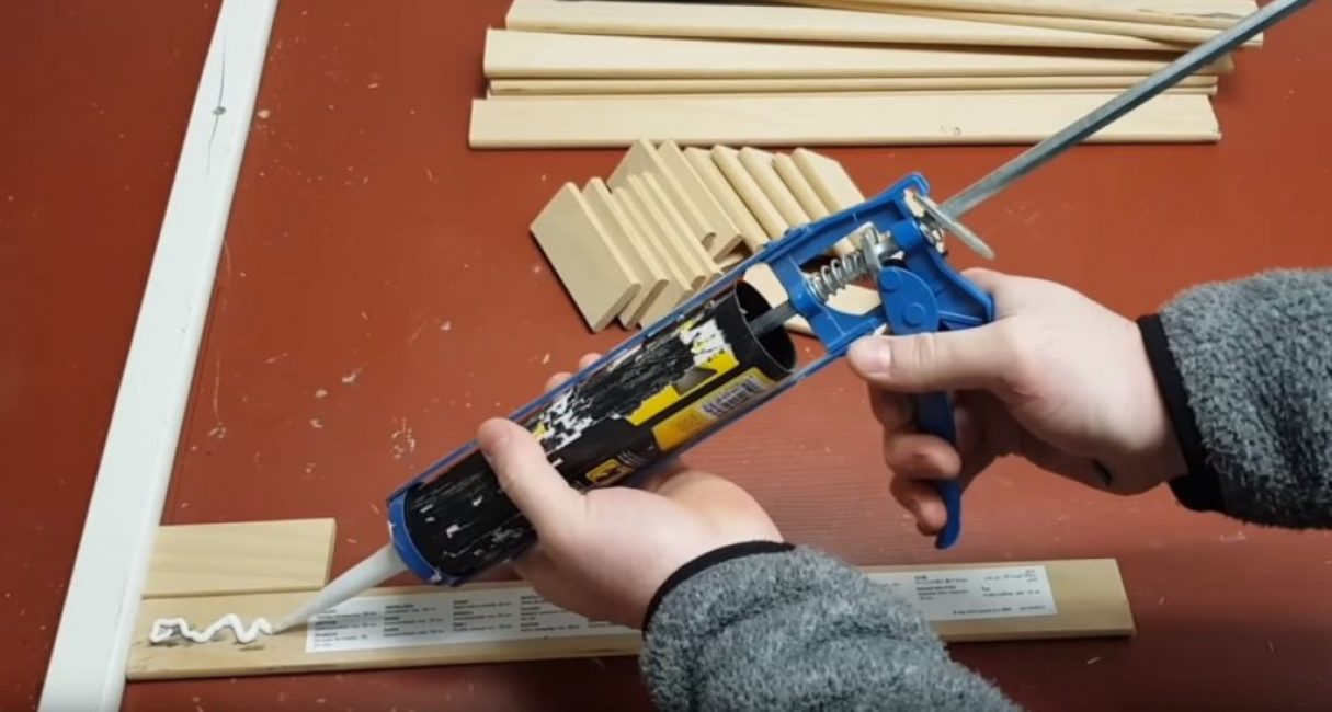 Une longue planche est appliquée sur la règle, sur les bords de laquelle de la colle est appliquée
