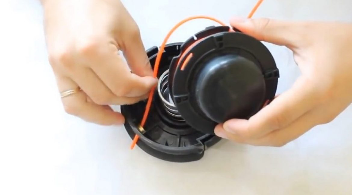 Les extrémités fixes de la ligne enroulée sont insérées dans les trous du corps de la bobine de la tondeuse