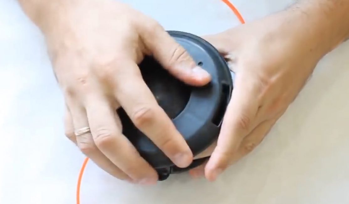 La bobine avec le bouton s'enclenche dans le corps de la bobine de la tondeuse