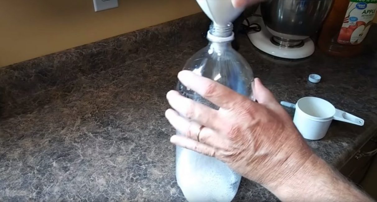 À l'aide d'un entonnoir, 100 à 150 g de sucre sont versés dans la bouteille