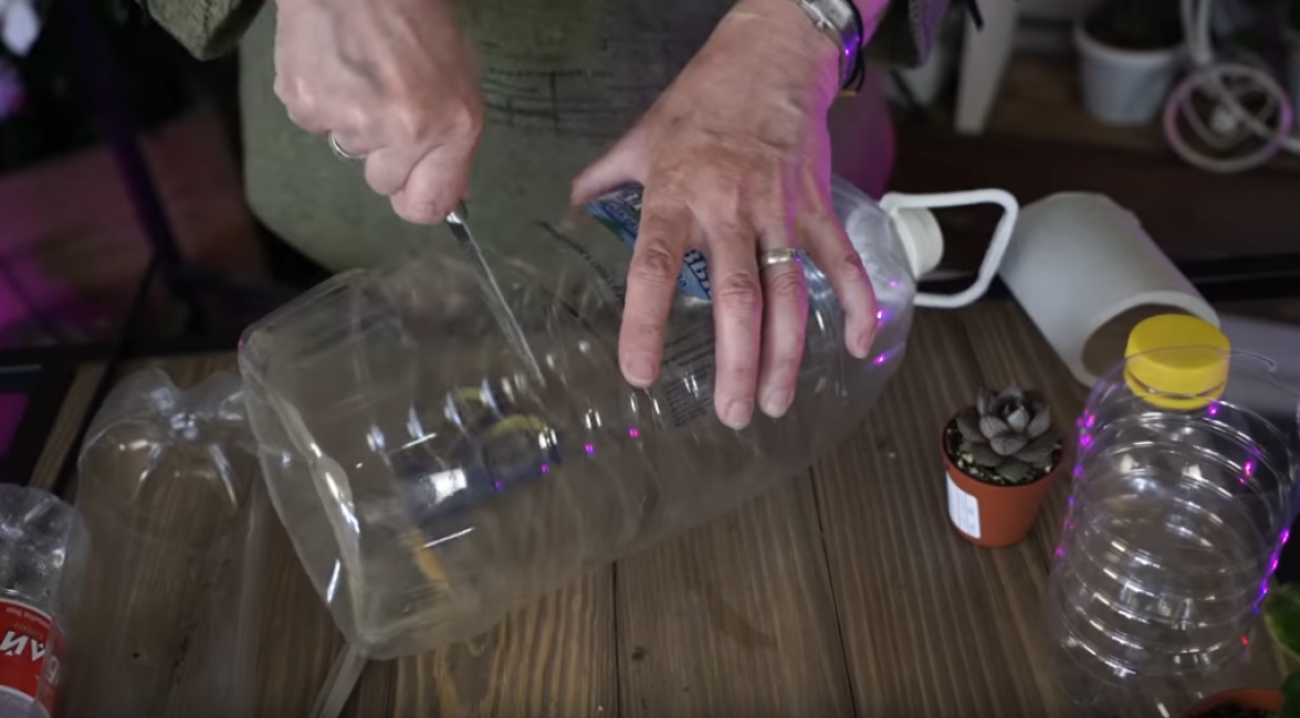 Nous coupons une grande bouteille en plastique avec une poignée et un couvercle en deux moitiés avec un couteau bien aiguisé.