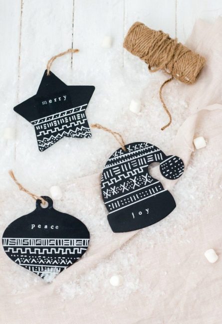 Les décorations en papier épais noir brillant ont un aspect très brutal. À partir de là, vous pouvez découper toutes les formes du thème du Nouvel An et appliquer des ornements avec de la peinture blanche. Comme suspension - ficelle de jute écologique