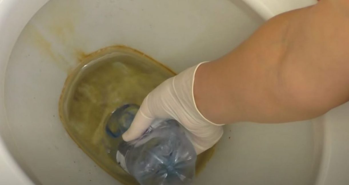 En pressant une bouteille en plastique, abaissez son goulot dans les toilettes